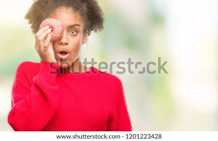 Young afro american woman eating donut over isolated background scared in shock with a surprise face, afraid and excited with fear expression