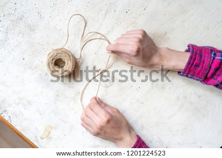 hands make a knot of a thick rope with a rope ball