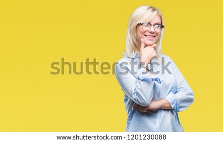 Young beautiful blonde business woman wearing glasses over isolated background looking confident at the camera with smile with crossed arms and hand raised on chin. Thinking positive.