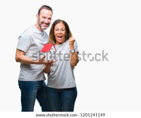 Middle age hispanic casual couple buying new house over isolated background screaming proud and celebrating victory and success very excited, cheering emotion