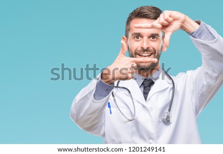 Young handsome doctor man over isolated background smiling making frame with hands and fingers with happy face. Creativity and photography concept.