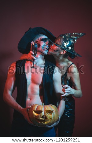 Halloween Zombie party and horror. Halloween Holiday and celebration. Couple in love with pumpkin and wine glass. woman and man in witch hat. couple with makeup on face on brown background.