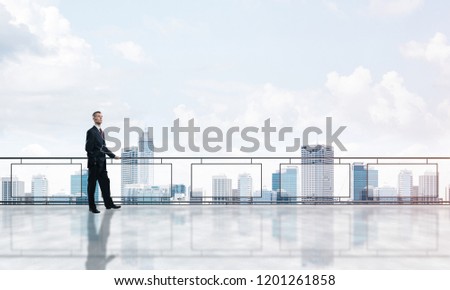 Young businessman in suit at balcony against morning cityscape background