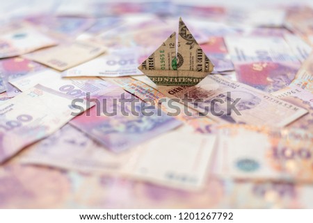 Flotant origami dollar on a background of argentinian pesos
