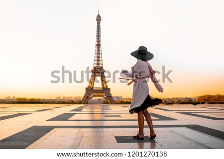 Woman dressed in coat and hat walking on the famous square with great view on the Eiffel tower early in the morning in Paris Royalty-Free Stock Photo #1201270138