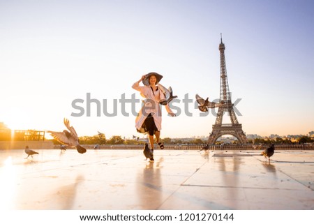 Woman running on the famous square dispersing pigeons with great view on the Eiffel tower early in the morning in Paris Royalty-Free Stock Photo #1201270144