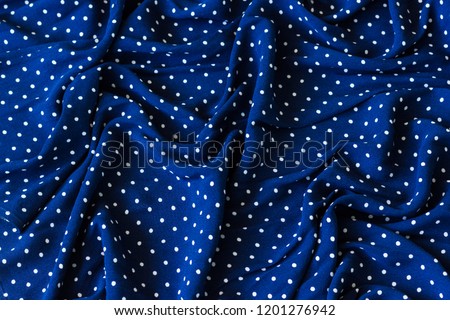 Wrinkled marine blue fabric with white dots. Creased textile, fashion swatch, background texture, seamless concepts