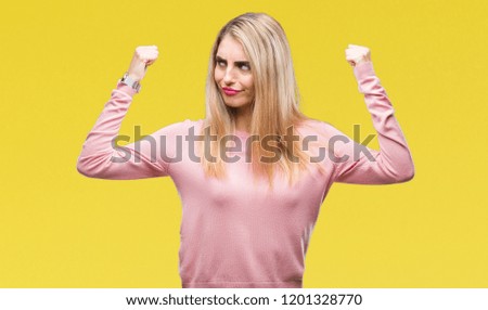 Young beautiful blonde woman wearing pink winter sweater over isolated background showing arms muscles smiling proud. Fitness concept.