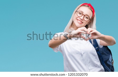 Young blonde student woman wearing glasses and backpack over isolated background smiling in love showing heart symbol and shape with hands. Romantic concept.