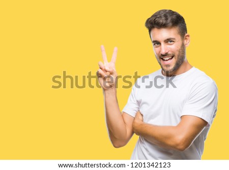 Young handsome man over isolated background smiling with happy face winking at the camera doing victory sign. Number two.
