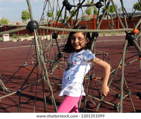 Beautiful girl playing on the playground in children's park.