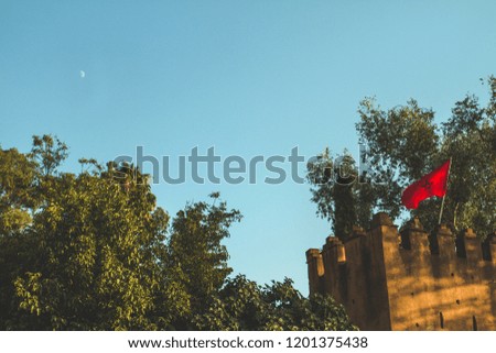 Morocco national red flag during the day and the moon behind