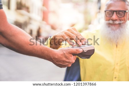 Male customer paying with contactless credit card with NFC technology - Waiter with a credit card reader machine at bar outdoor - New tech payment concept - Focus on bearded man hand