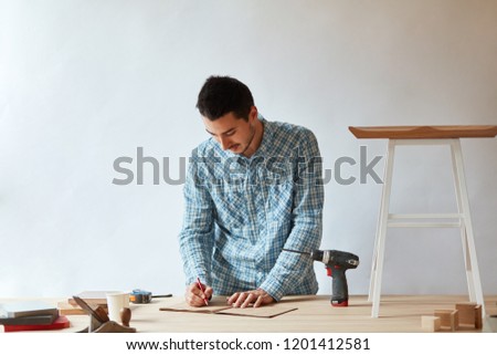 Caucasian male carpenter planning a drawing of his new piece of furniture. Craftsman Handicraft Wooden Workshop Concept