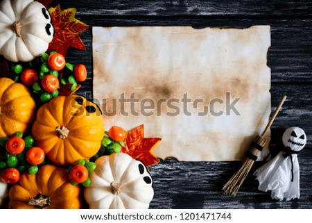 Top view of white and yellow ghost pumpkins with Colorful Autumn leaves and old paper on a black wooden table background. halloween concept.