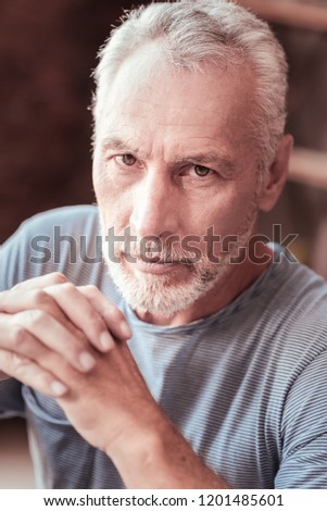 Calmness. Portrait of elderly man having peaceful mood while looking at you and keeping fingers crossed