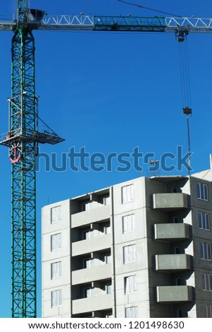 Construction of a residential high-rise building. Photo of a construction crane installing floor decks