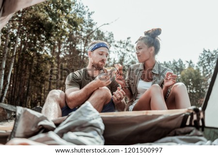Suntanned backpackers. Suntanned backpackers feeling rested and relaxed while eating delicious sandwiches near their tent