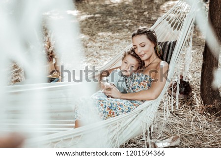 Mother care. Happy nice mother and son lying in a hammock resting together