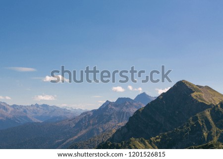 The peak of high mountains. Bright day sun in the mountain autumn forest. Blue clear sky