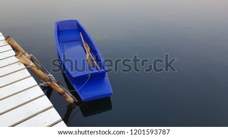 Blue ship and white wood bridge in peaceful lake