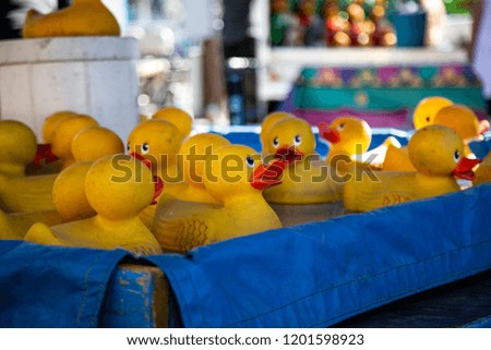 Low level view of many yellow rubber duckies in a pool of water at the state fair with out of focus background
