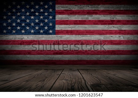 Flag of United States of America on brick old wall. Dark room with wooden floor.