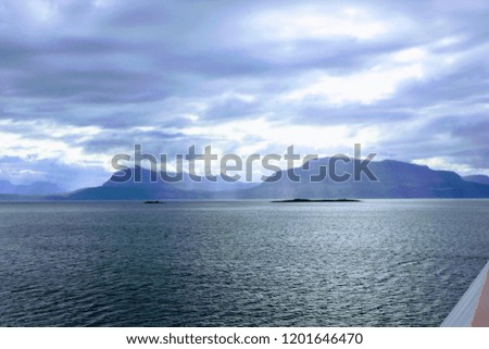 light rays shining through the clouds in norway fjord blue with sea in front and mountains in the background