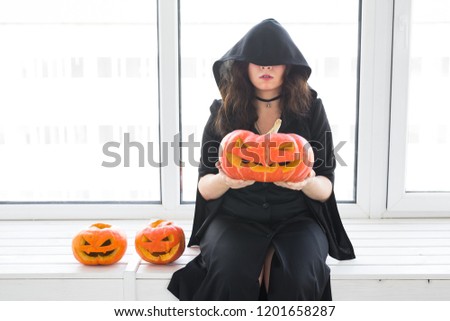 Halloween and holidays concept - Witch woman with Jack O'Lantern pumpkin