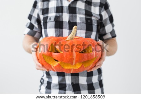 Halloween, holidays and autumn concept - Close up of man holding a jack-o-lantern pumpkin.