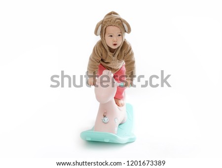     Cute baby riding a wooden horse with a white background  