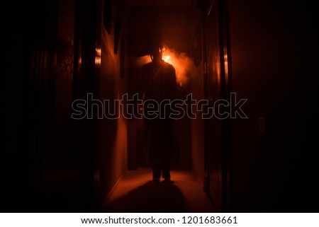 Creepy silhouette in the dark abandoned building. Horror Halloween concept. Dark corridor with silhouette of horror person standing in center. Toned light and fog on background.