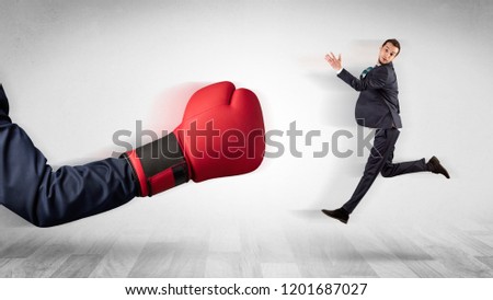 Big red boxing glove knocks out little businessman concept