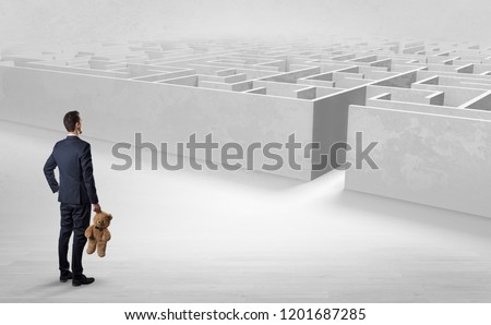 Businessman getting ready to enter the labyrinth with objects in his hand concept