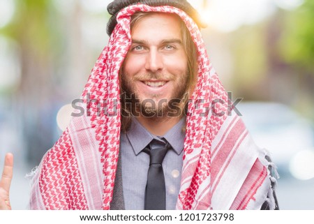Young handsome arabian man with long hair wearing keffiyeh over isolated background showing and pointing up with fingers number four while smiling confident and happy.