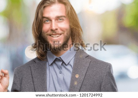 Young handsome business man with long hair over isolated background with a big smile on face, pointing with hand and finger to the side looking at the camera.