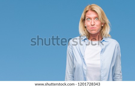 Middle age blonde woman over isolated background puffing cheeks with funny face. Mouth inflated with air, crazy expression.