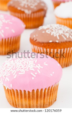 Close up of many muffins with icing sugar against a white background