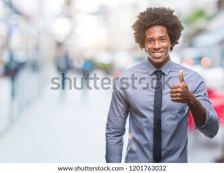 Afro american business man over isolated background doing happy thumbs up gesture with hand. Approving expression looking at the camera with showing success.