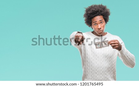 Afro american man holding one dollar over isolated background pointing with finger to the camera and to you, hand sign, positive and confident gesture from the front