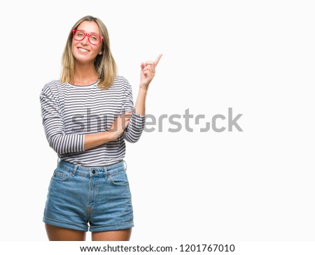 Young beautiful woman wearing glasses over isolated background with a big smile on face, pointing with hand and finger to the side looking at the camera.