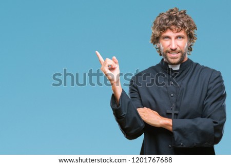 Handsome hispanic catholic priest man over isolated background with a big smile on face, pointing with hand and finger to the side looking at the camera.