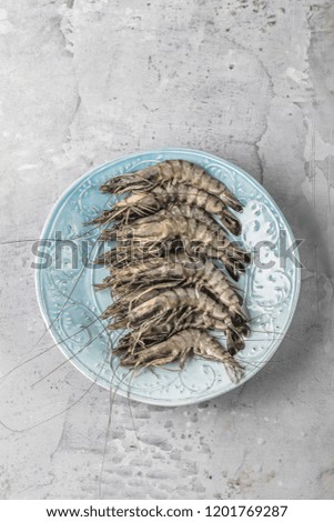 fresh shrimps or prawns raw on kitchen table board with ingredients