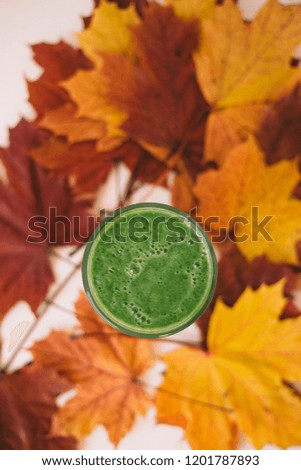 Green smoothies on autumn Multicolored fallen leaves