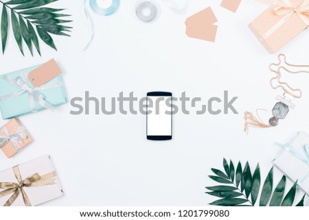 Summer arrangement with palm branches, gifts, ribbons and smart phone, top view. Flat lay composition empty screen of mobile device on white background.