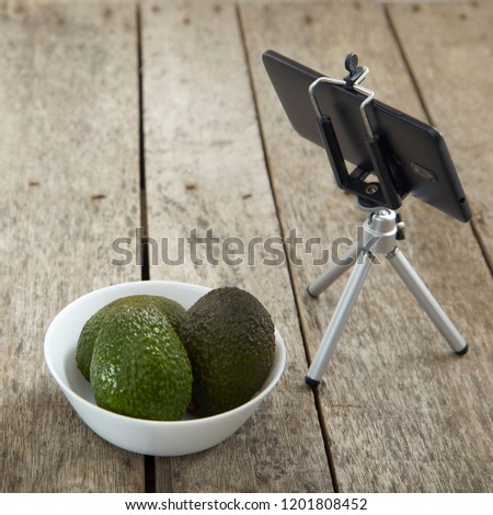 Smartphone Tripod capture with Avocado Sell on a wooden table, Empty space for
design ,Business concept photography