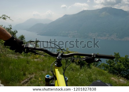 hand of man with yellow electric bicycle, e-bike, ebike, mountain, valley, lake of Como, summer, sport, adventure, sun, alps, Italy
