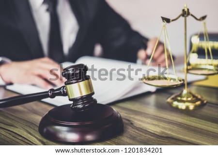 Judge gavel with Justice lawyers, Gavel on wooden table and Counselor or Male lawyer working on a documents at law firm in office. Legal law, advice and justice concept.