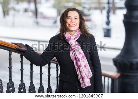 People, fashion and season concept - young stylish woman in coat posing on stairs in winter day