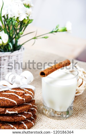 Closeup picture of crunchy cookies and milk glass with cinnamon stick on it